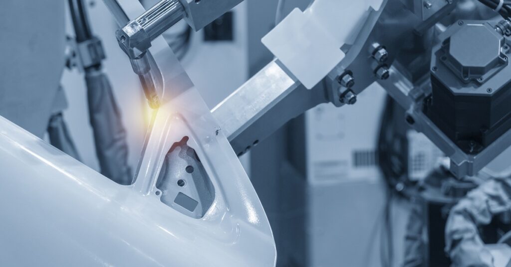 Automotive manufacturing arm welding a thick piece of metal with precision