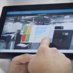 Worker touching tablet´s screen, which has Critical Manufacturing´s MES open