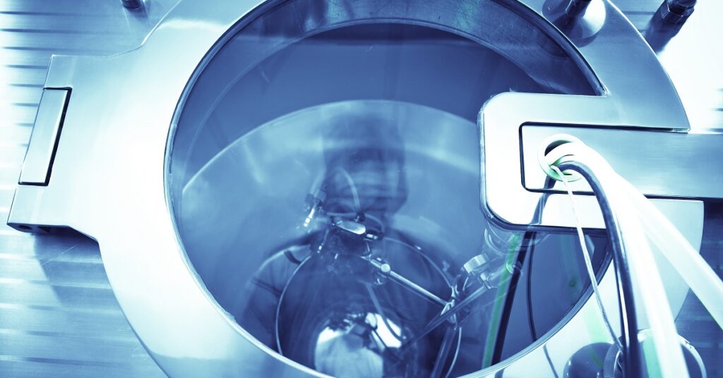 Technician operates a machine in a sterilization lab, ensuring safety protocols during the COVID-19 pandemic.