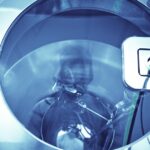 Technician operates a machine in a sterilization lab, ensuring safety protocols during the COVID-19 pandemic.