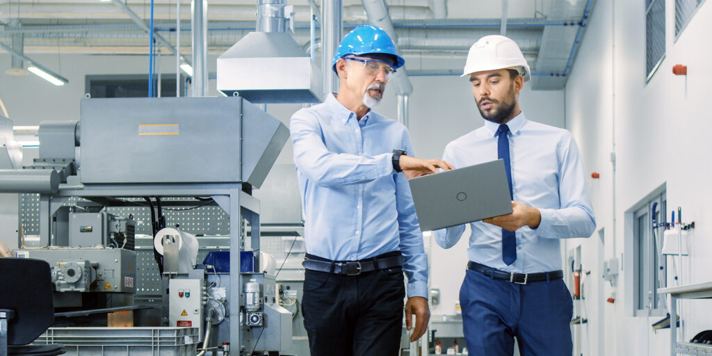 Two men in hard hats collaborate in a factory, showcasing a complete modular solution for efficient production processes.