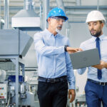 Two men in hard hats collaborate in a factory, showcasing a complete modular solution for efficient production processes.