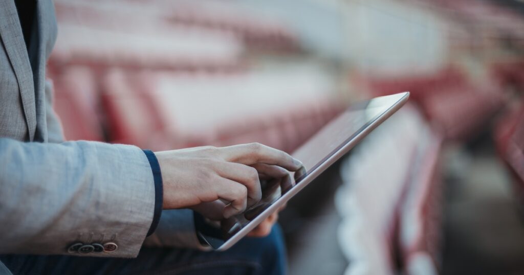 Young man using digital tablet on the empty football stadium