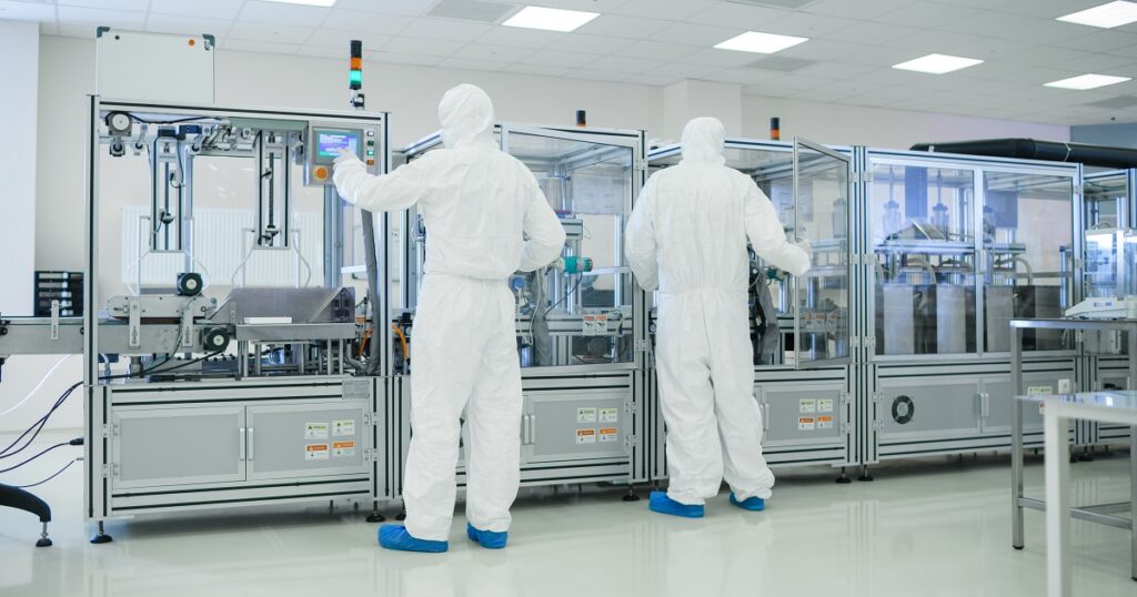 Manufacturing Facility Team of Scientist Wearing Sterile Protective Coverall Set's up / Programs Modern Industrial 3D Printer, High Precision Manufacture of Semiconductors under Process