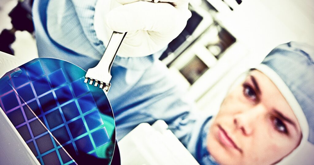Female scientist in blue overalls is carefully holding a silicon wafer, reflecting her involvement and determination in a semiconductor environment.
