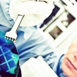 Female scientist in blue overalls is carefully holding a silicon wafer, reflecting her involvement and determination in a semiconductor environment.