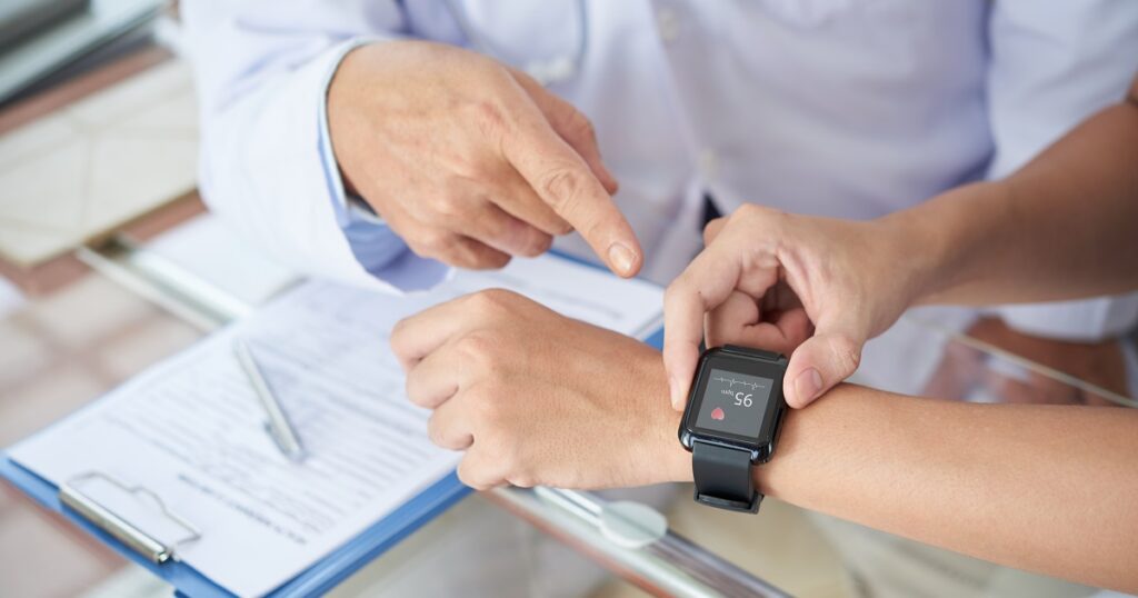 Doctor examines a patient's wrist, who is wearing a medical device for monitoring health conditions.