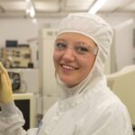 Young Woman in Clean Suit Working in Semiconductor Manufacturing Environment or Cleanroom