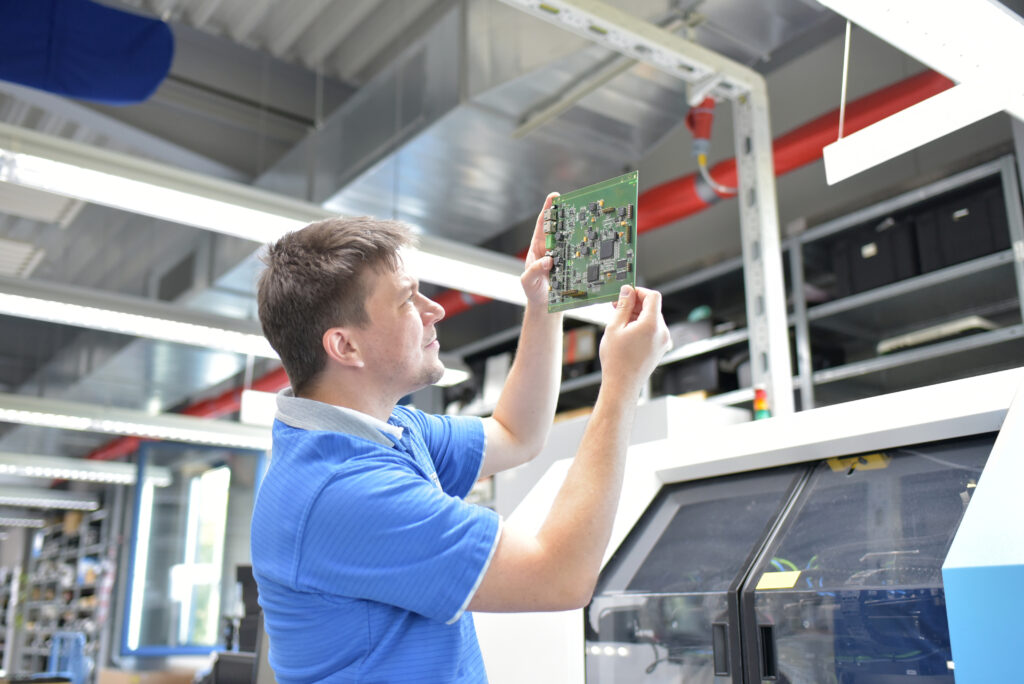 Male worker analyzing a semiconductor piece, in a factory.