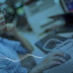 Woman wearing glasses interacting with her laptop mouse, pursuing manufacturing excellence, with Vishay logo visible in the left top corner.